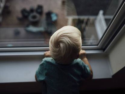 Un bebé mira por una ventana.
