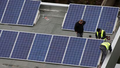 Operarios instalan paneles solares en una cubierta de un edificio.