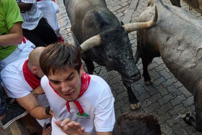 Un corredor trata de zafarse de los cuernos de uno de los toros de José Escolar, en el tramo de Telefónica, durante el tercer encierro de San Fermín.