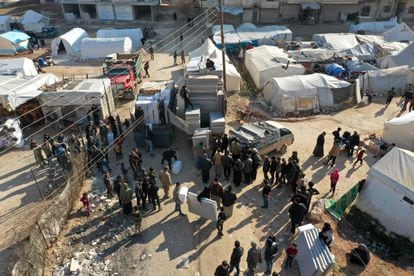 En esta vista aérea, personas que viven en tiendas de campaña tras el terremoto de magnitud 7,8 que sacudió Turquía y Siria el 6 de febrero, reciben colchones y otra ayuda humanitaria distribuida por una ONG, en la ciudad de Afrin, en la parte de la provincia de Alepo controlada por los rebeldes, el 16 de febrero de 2023. 