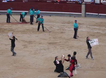 El mozo de banderillas intenta arrebatar una de las pancartas que llevaban los antitaurinos que han saltado al ruedo de Las Ventas.