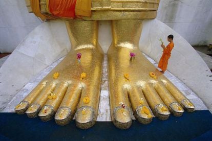 Un monje a los pies de la estatua gigante de buda en el templo de Wat Intharawihan, en Bangkok.