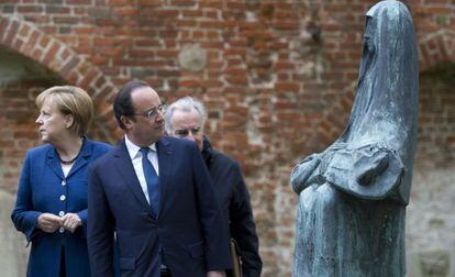 El presidente francés François Hollande mira una escultura durante una visita junto a Angela Merkel a un convento en Stralsund, al noreste de Alemania.