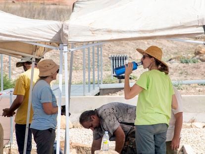 Un grupo de arqueólogos se protegen a mediodía del sol en Jaén, con sombreros, toldos para el trabajo y agua.