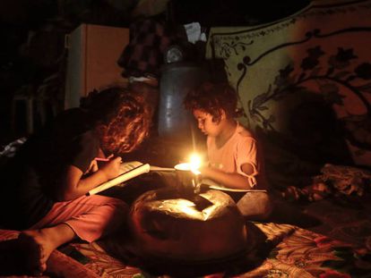 Dos ni&ntilde;os palestinos hacen los deberes durante un apag&oacute;n en Gaza.
