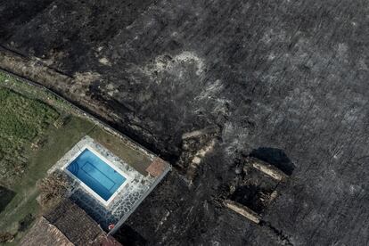 Fotografía tomada con un dron de una piscina y una construcción rodeadas por la superficie calcinada en el pueblo de San Cibrao (Oímbra), este viernes.