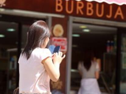 Una mujer consulta el m&oacute;vil en la calle.