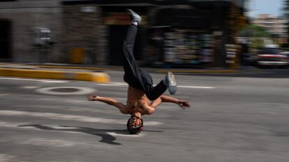 B-boy Kenyer Méndez, de 27 años, desliza su cabeza, usando un casco modificado frente a un semáforo, en Caracas.