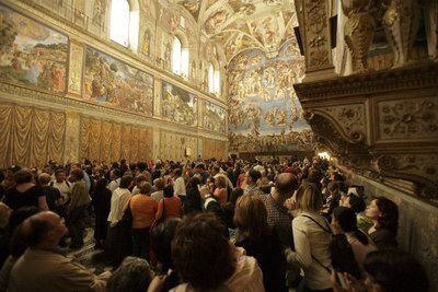 Visitantes de la Capilla Sixtina contemplan los frescos de Botticelli, Ghirlangaio y Rosselli (de izquierda a derecha), bajo la cúpula y el frontispicio de Miguel Ángel.