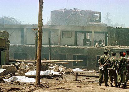 Varios soldados observan los cadáveres de varias víctimas, cubiertos por mantas, en las ruinas del hotel Paraíso.