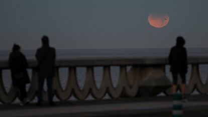 Tres personas observan el eclipse lunar parcial desde A Coruña, este viernes, en A Coruña, Galicia.