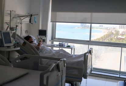 Un paciente con covid mira el móvil desde una habitación del Hospital del Mar de Barcelona, donde está ingresado