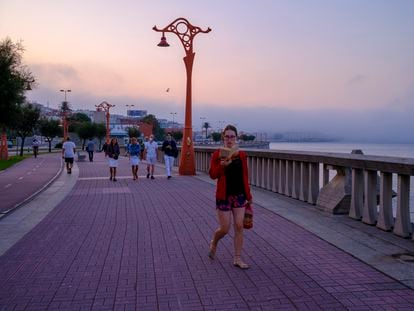 Una mujer lee mientras pasea, en La Coruña, este agosto.