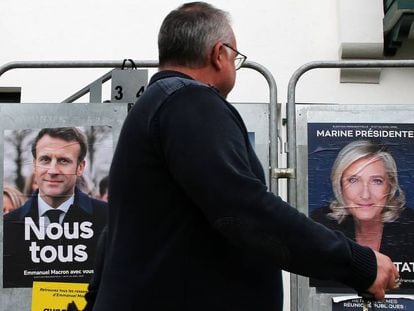 Un peatón camina frente a carteles de la campaña presidencial de Emmanuel Macron y Marine Le Pen