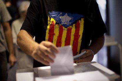 Un votante con la bandera independentista catalana deja su voto en Barcelona, en las elecciones del 27 de septiembre de 2015.