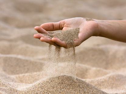 Una mano sosteniendo un puñado de arena.