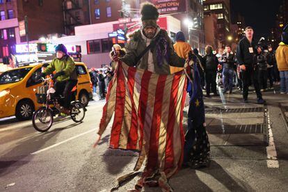 Una persona sostiene la bandera de Estados Unidos quemada durante las protestas en Nueva York, el jueves. 