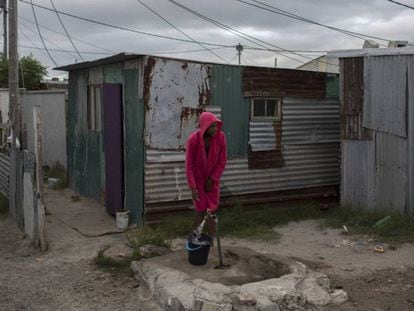 Mujer recoje agua en un asentamiento cerca de Ciudad del Cabo
