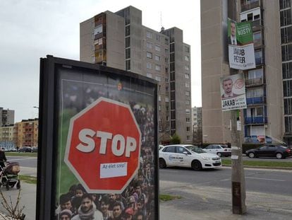 Una familia pasea junto a un cartel de la campaña estatal contra la inmigración, en Miskolc (Hungría), este miércoles.