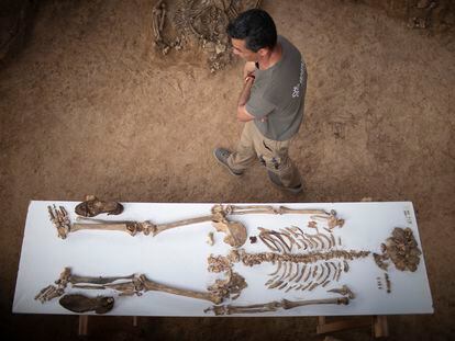 Uno de los técnicos que trabaja en la fosa de Pico Reja pasa junto a una mesa con los restos y enseres personales de uno de los integrantes de la Columna Minera.