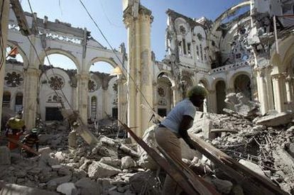 Varias personas buscan entre los escombros de la catedral de Puerto Príncipe material para reconstruir casas.