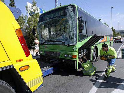 Empleados de la grúa se disponen a remolcar uno de los autobuses implicados en el accidente de la A-1.