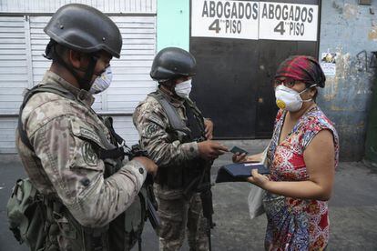Dos soldados detienen a una mujer en un retén en el tercer día del estado de emergencia en Lima, Perú, este miércoles.