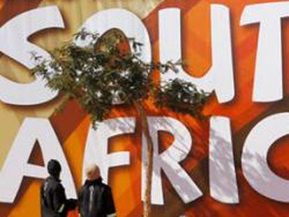 Varios obreros levantan un cartel gigante en el estadio Ciudad del Fútbol en Johannesburgo (Sudáfrica).