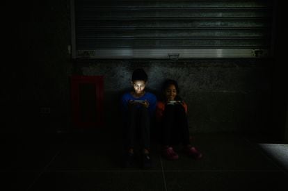 Dos niños juegan en sus teléfonos durante una falla de servicio eléctrico.