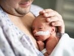 Un padre cuida de su bebé prematuro haciendo piel a la piel en el hospital.