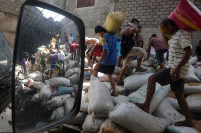 Supervivientes de la zona cargan sacos de arroz en un almacén devastado por el tifón.