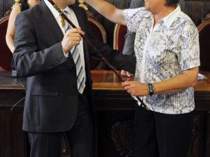 El nuevo alcalde de Girona, el convergente Carles Puiddemont, recibe la vara de alcalde de manos de la hasta ahora alcaldesa, la socialista Anna Pagans.