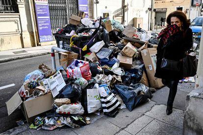 Una mujer camina al lado de gran cantidad de basura en una calle de Marsella (Francia). Los sindicatos FSU y CGT han llamado a bloquear dos centros de transferencia de residuos durante 10 días en protesta contra la reforma de las pensiones.