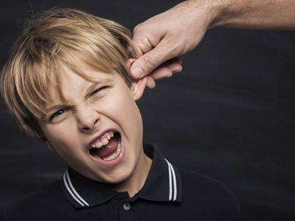 Un padre tira de la oreja a su hijo.