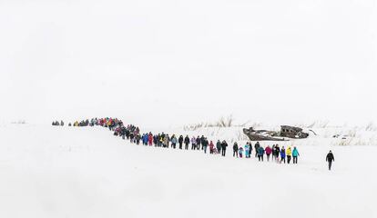 El público de la fiesta de los pastores de renos de Dudinka, caminando a lo largo de un río cubierto de nieve.