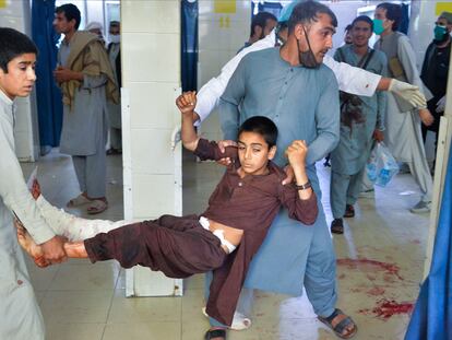 Dos voluntarios llevan a un menor herido tras el ataque en un funeral en Nangarhar, en el este de Afganistán.