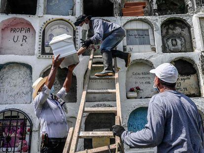 Un familiar de una víctima del conflicto armado colombiano entrega la urna con los restos de sus seres queridos a un sepulturero en el cementerio de Dabeiba (Colombia).