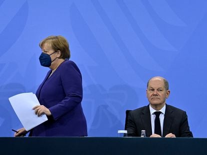La canciller en funciones, Angela Merkel, llega a la rueda de prensa para anunciar las nuevas restricciones y se sienta junto a su sucesor, Olaf Scholz, este jueves en Berlín.