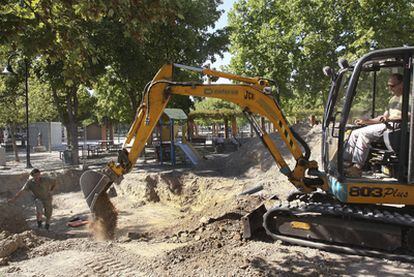 Una excavadora escarba en el parque infantil bajo el que se hallan los cuerpos.