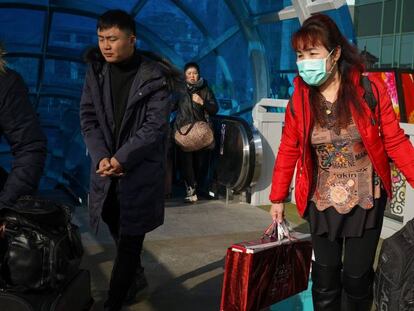 Viajeros dispuestos con mascarillas esperan la salida en la estación de tren de tren de Pekín. 