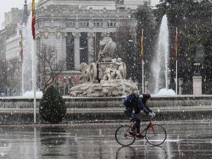 Un ciclista circulaba a las dos de la tarde de ayer junto a la estatua de la Cibeles durante la nevada.