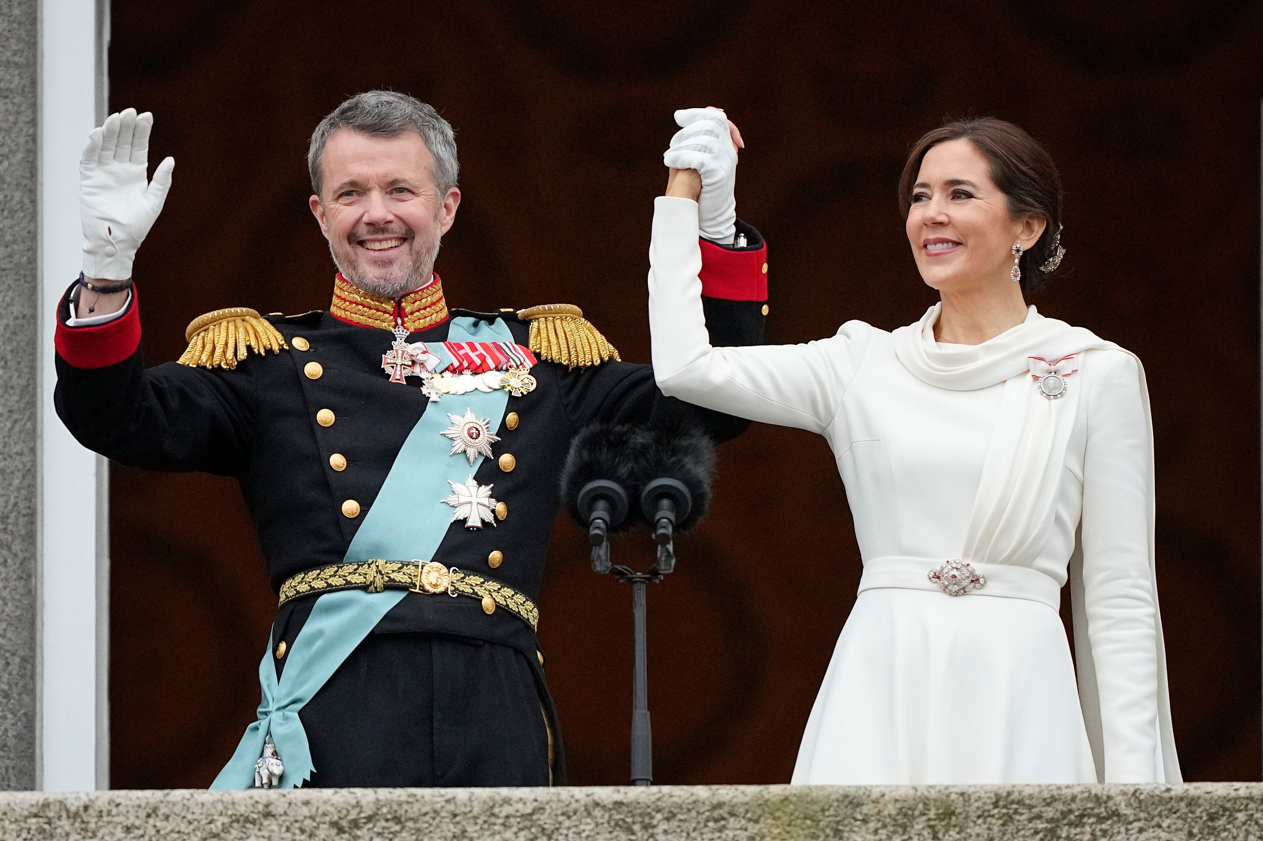 El rey Federico X y la reina María de Dinamarca saludan desde el balcón de la sede del Parlamento. 