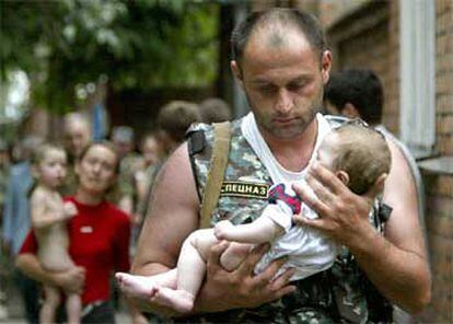 Un policía ruso sujeta en sus brazos a un bebé liberado por los terroristas.