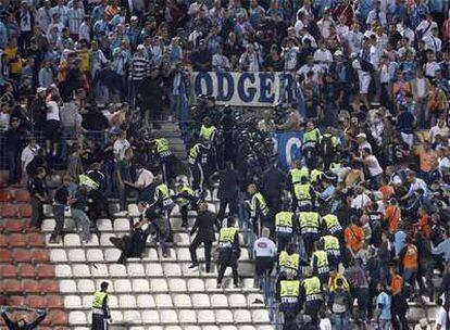 Miembros de seguridad de la UEFA y agentes antidisturbios cargan contra hinchas del Marsella.