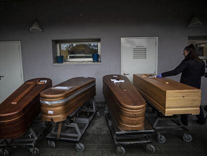 Una empleada del Crematorio Sur de Madrid, junto a varios féretros de fallecidos con coronavirus a las puertas de la zona de incineración.