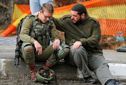 A las 11:30 de la mañana del jueves 13 de diciembre de 2018 un palestino descendió de su vehículo ante una parada de autobús y punto de recogida de autoestopistas y abrió fuego a bocajarro contra un grupo de militares israelíes en el cruce de Asaf, uno de los principales accesos a Ramala (Cisjordania). En la imagen, un soldado israelí es consolado mientras la policía forense inspecciona el lugar del ataque.