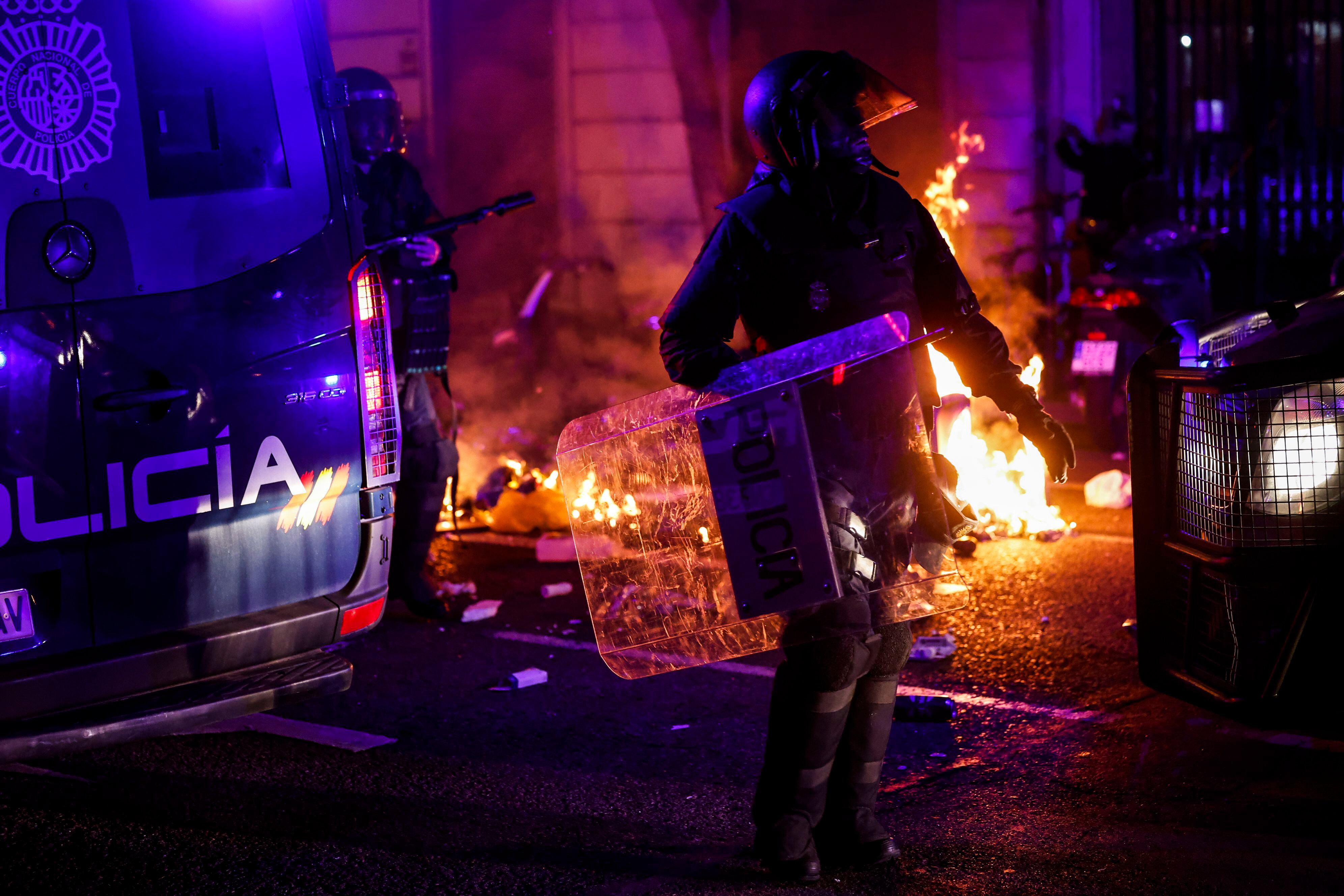 Un policía se abre paso entre los furgones y el fuego provocado por los ultras. 