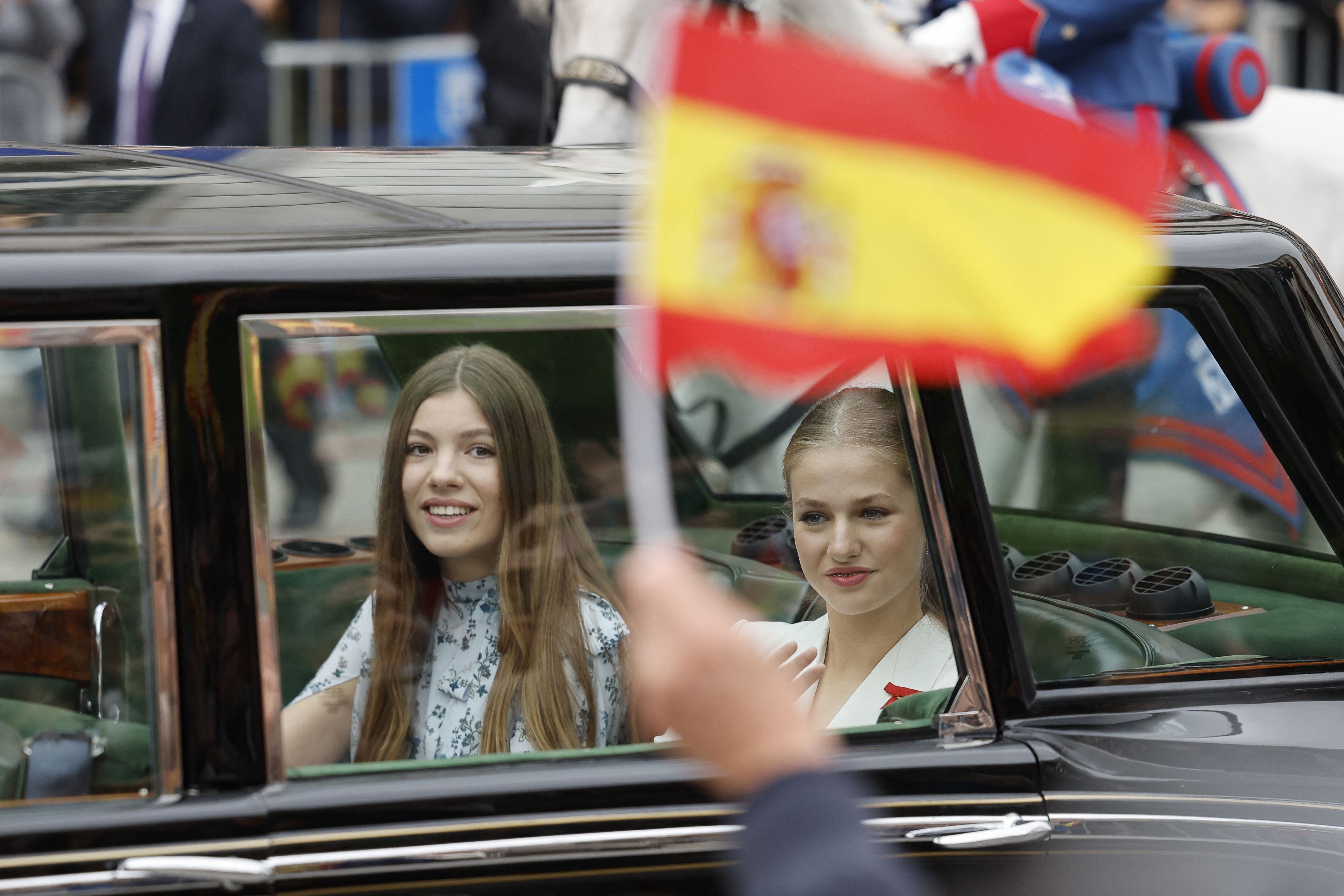 La infanta Sofía y la princesa de Asturias, Leonor de Borbón, saludan a los ciudadanos al paso de la comitiva real por las calles del centro de Madrid. 