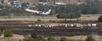 Un avión sobrevuela la zona del accidente, donde pueden verse los servicios de emergencia, tras despegar del aeropuerto de barajas ayer por la tarde, una vez el tráfico fue restablecido.