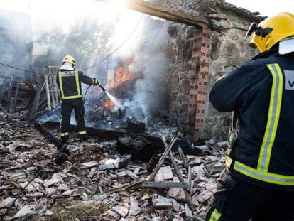 Dos bomberos sofocan un incendio en una vivienda afectada por la explosión.